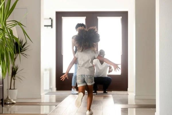 Afrikanische kleine Tochter rennt zu Eltern, die vor der Tür stehen — Stockfoto