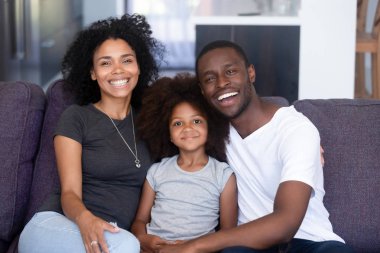 Afrikalı aile ve kızı kanepede oturan kamera için poz