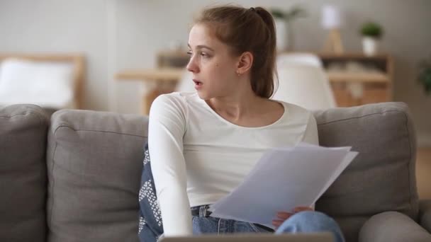 Young woman siting on couch holding documents papers feels frustrated — Stock Video