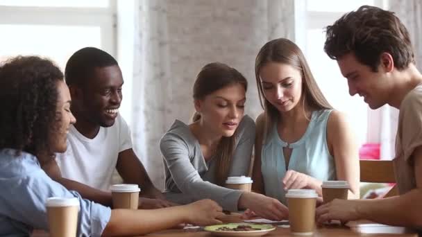 Millennial diferentes amigos étnicos sentados a la mesa ensamblando rompecabezas — Vídeos de Stock