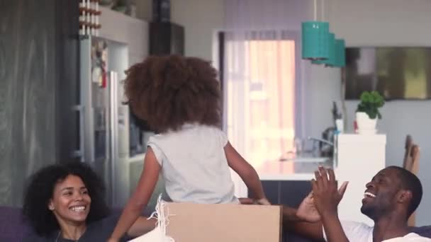 アフリカの家族は、新しい家で引っ越しを祝う娘と遊びます — ストック動画