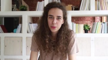 Genç kadın kamera bakarak web kamerası üzerinden kapalı görüşmeler oturuyor