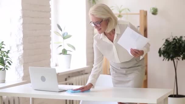 Mujer de negocios positiva prepara su mesa de toallitas de trabajo con trapo — Vídeos de Stock