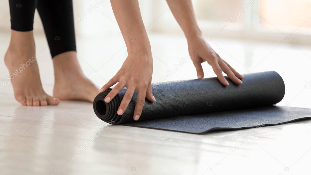 Woman wearing black leggings finished workout rolling mat closeup image