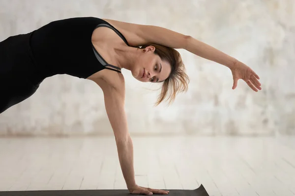 Beautiful woman performing Bending Side Plank yoga asana indoors — Stock Photo, Image