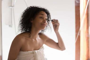 Güzel karışık ırk kadın maskara uygulayarak aynaya bakıyor