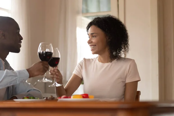 African married couple celebrating clinking glasses toasting holding red wine — Stock Photo, Image