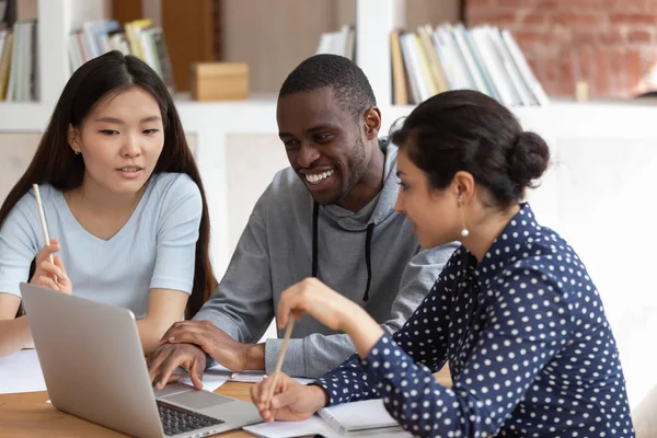 Smiling diverse students talk working on laptop together — Stock Photo, Image