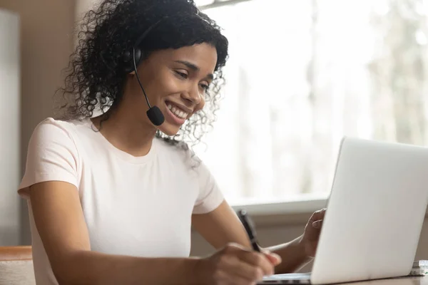 Smiling african woman wearing headphones listening audio course using laptop — Stock Photo, Image