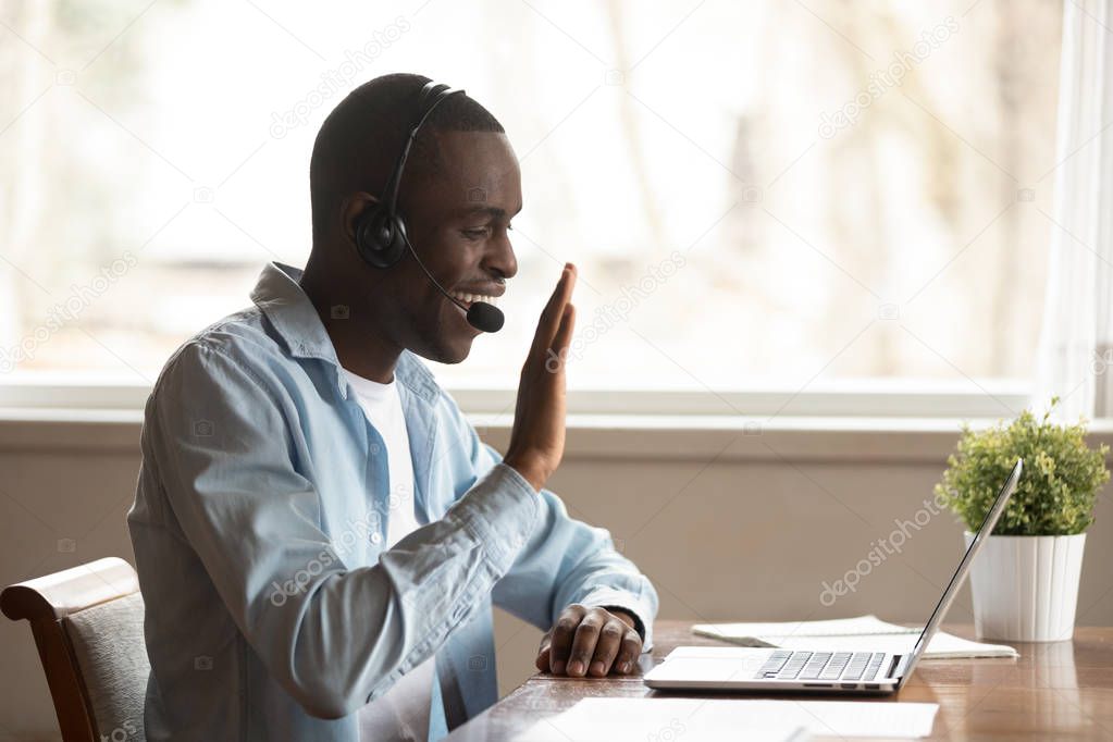 African guy wearing headset starting lesson online greeting tutor