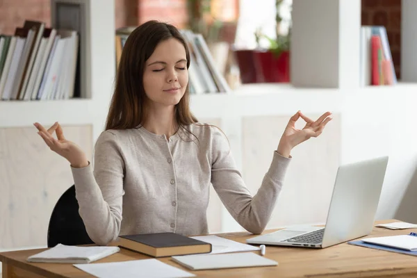 Vreedzaam meisje afgeleid van het bestuderen van mediteren op de werkplek — Stockfoto