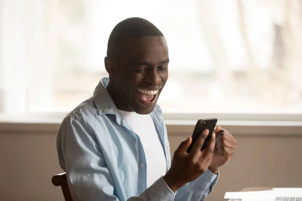 Africano mirar el teléfono celular leer grandes noticias se siente feliz — Foto de Stock