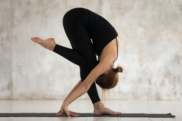 Mujer joven realizando yoga asana De pie hacia adelante Doblar en el interior — Foto de Stock