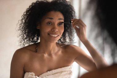 Yakın makara uygulayarak aynaya bakan karışık ırk kadın kadar