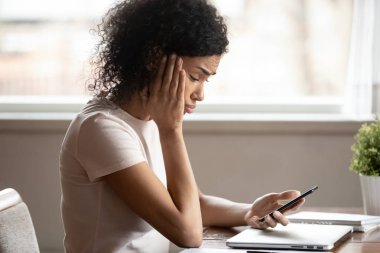 Cep telefonu ekranına bakan Afrikalı kadın üzgün hissediyor