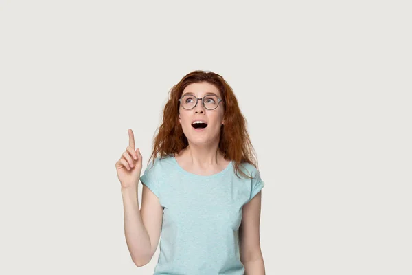 Sbalordita rossa donna puntando il dito verso il copyspace studio shot — Foto Stock