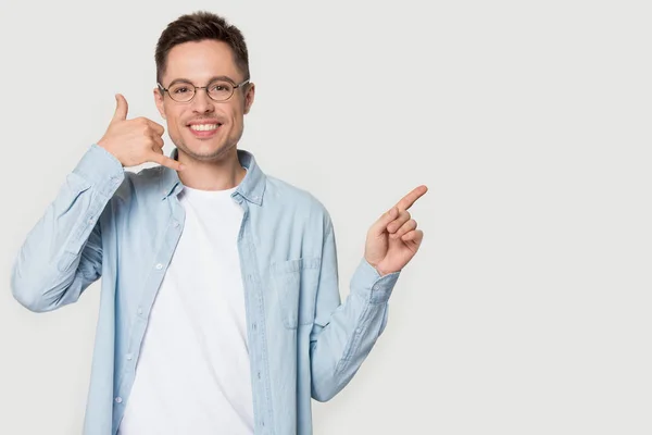 Man makes call me gesture pointing finger aside at announcement — Stock Photo, Image
