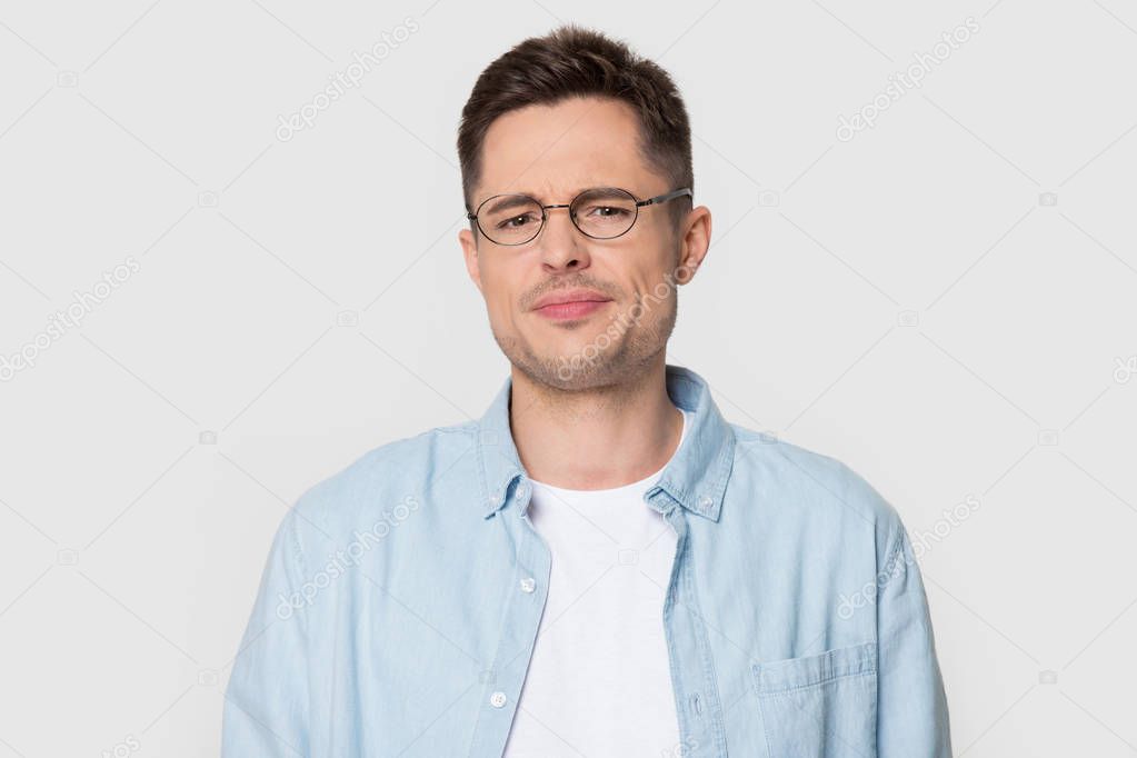 Headshot portrait dissatisfied frowning guy posing over studio background