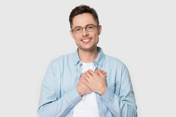 Młody mężczyzna w okularach trzyma ręce na klatce piersiowej czuje wdzięczność — Zdjęcie stockowe