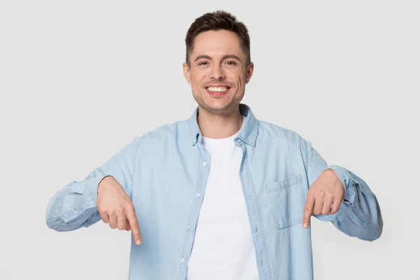 Hombre feliz aislado sobre fondo gris apuntando con los dedos hacia abajo — Foto de Stock