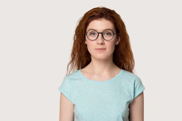 灰色の背景の上に眼鏡で深刻な赤毛の女性 — ストック写真