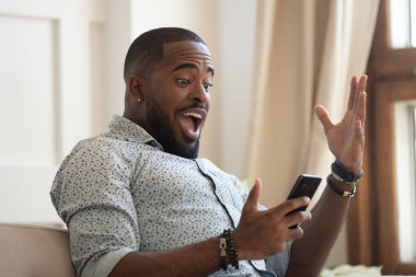 Sürpriz mutlu Afrikalı adam cep telefonu bakarak iyi haber okumak
