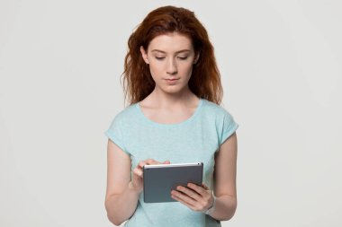 Tablet bilgisayar stüdyosu çekim kullanarak Ciddi kırmızı saçlı kadın