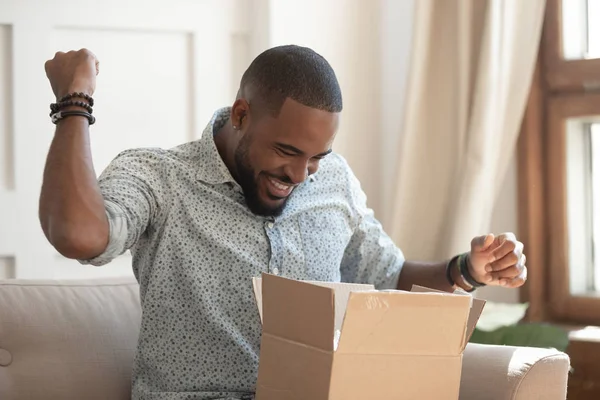 Excited african man customer receive open parcel box at home — Stock Photo, Image