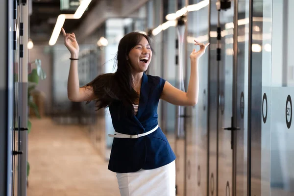 Excited funny young asian businesswoman celebrate success in victory dance