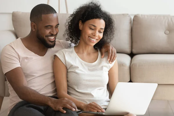 Feliz africano pareja usando laptop viendo película sentarse en piso —  Fotos de Stock