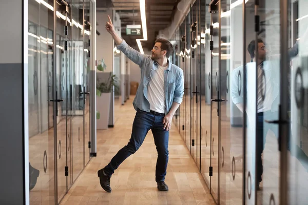 Funny excited young businessman winner dancing alone in office hallway