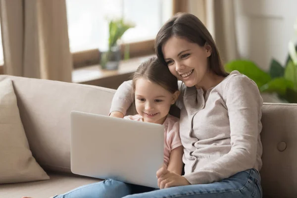 Matka s dcerou sedí na gauči a kouká na film na laptopu — Stock fotografie
