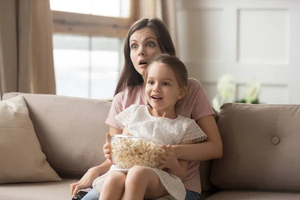 Madre hold hija en regazo viendo película se siente sorprendido —  Fotos de Stock