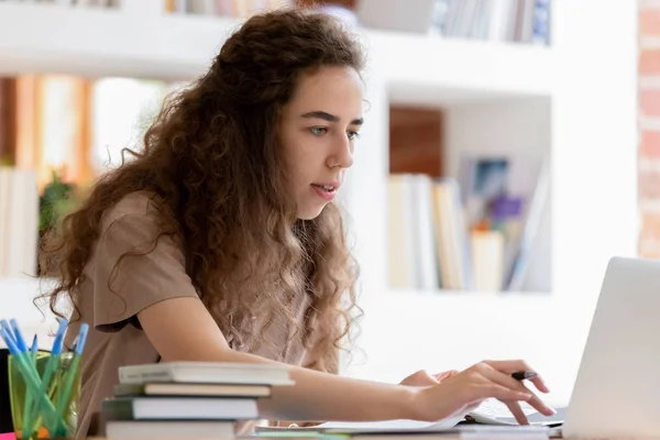 Serieuze student meisje studeren met behulp van laptop zittend op klas Bureau — Stockfoto