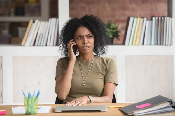 Frowning afrikansk affärskvinna som har obehagliga samtal på telefon — Stockfoto