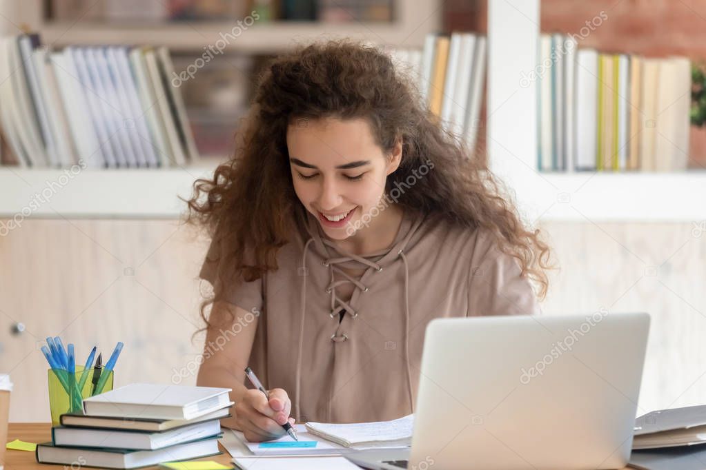 Student girl sitting at desk takes notes feels satisfied