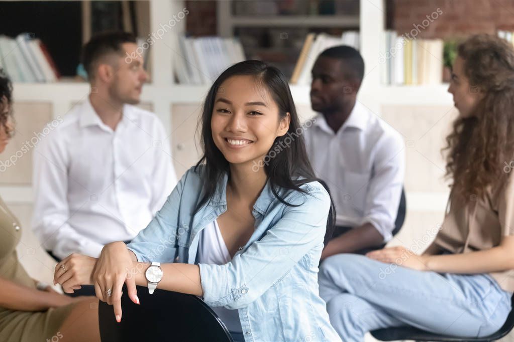 Asian addiction counsellor pose looking at camera during group rehab