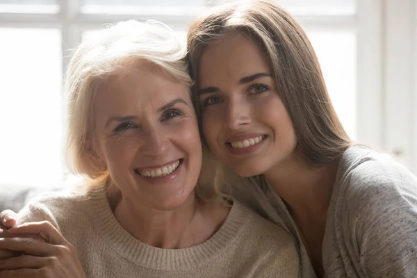 Middle aged mother grown up daughter embracing looking at camera — Stock Photo, Image