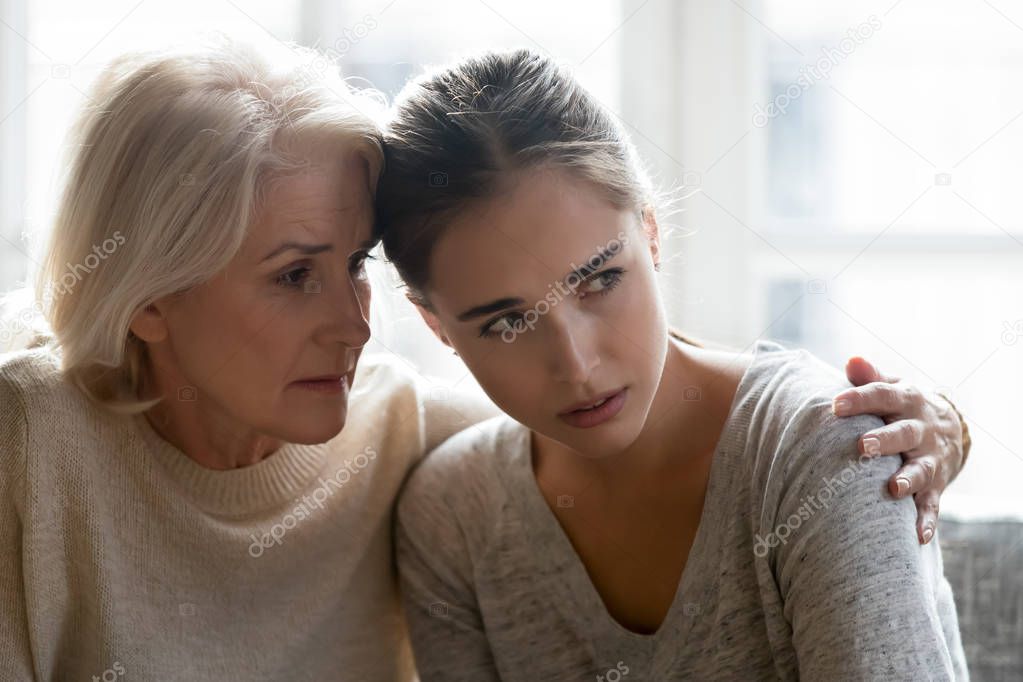 Aged mother calming grown up daughter close up image