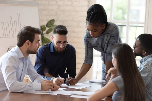 Serious african woman boss explain paperwork at group meeting