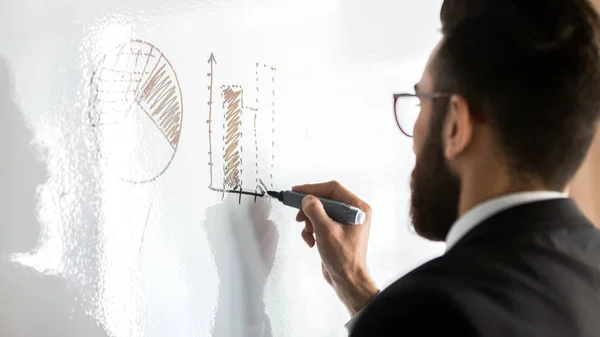 Close up businessman wearing glasses drawing graphs on flip chart — Stock Photo, Image