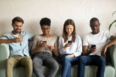 Kuyrukta bekleyen akıllı telefonları kullanan çok ırklı gençler