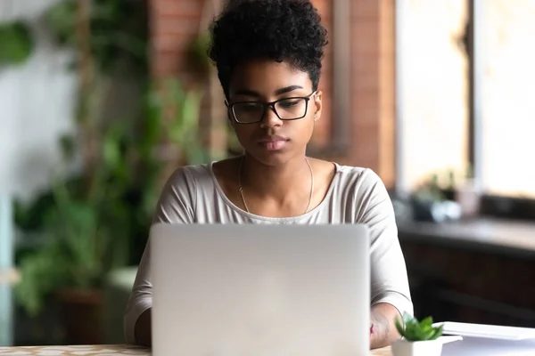 Enfocado biracial millennial chica ocupada trabajando en el ordenador portátil —  Fotos de Stock