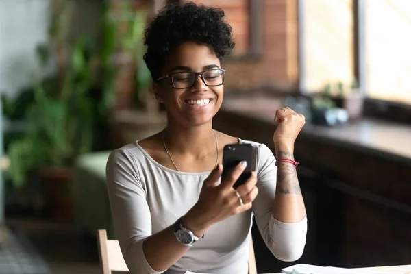 Excited black girl feel euphoric reading news on cell — Stock Photo, Image