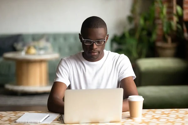 Focused black man studying on laptop drinking coffee — Stock Photo, Image