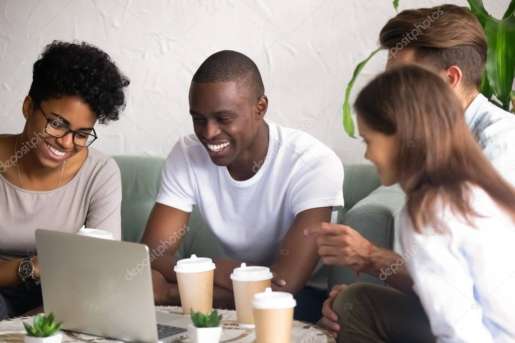 Happy diverse friends laugh hanging out in cafe