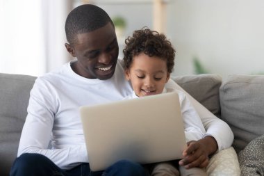 Sevimli çocuk çocuk mutlu siyah baba ile dizüstü bilgisayar kullanarak öğrenme