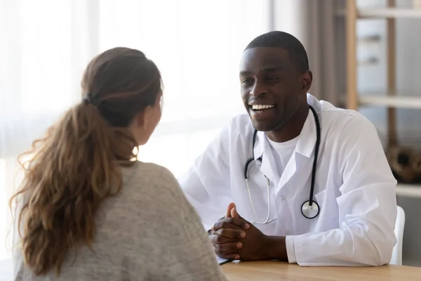 Leende svart manlig läkare lyssnar kvinnliga patienten vid läkar mötet — Stockfoto