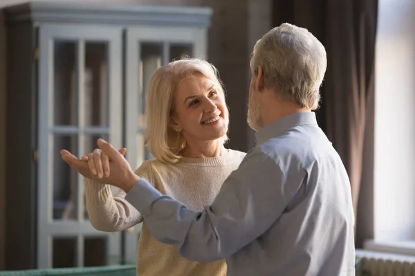 Happy romantic old senior couple dancing waltz at home