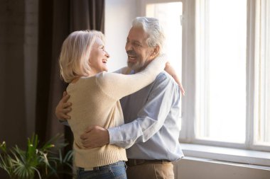 Mutlu yaşlı emekli romantik çift oturma odasında gülerek dans
